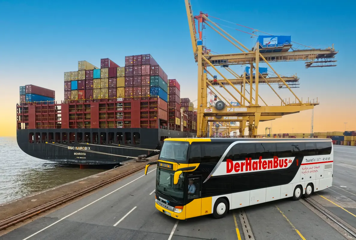 Der gelb-schwarz-weiße HafenBus fährt am Kaimauer-Terminal in Bremerhaven vor einem großen Containerschiff und Verladekränen.
