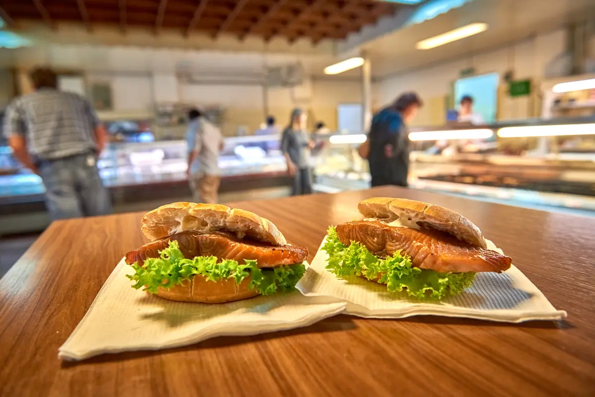 Zwei leckere Fischbrötchen mit Lachs und Salatblatt liegen auf Papierservietten auf einem Holztisch in Bremerhaven.