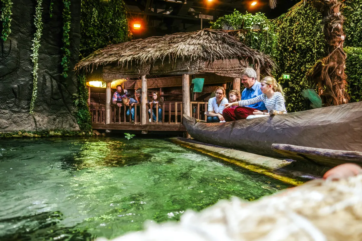 Eine Familie sitzt in einem Holzkanu an einem künstlichen Flusslauf in der tropischen Ausstellungs-Welt in Bremerhaven.