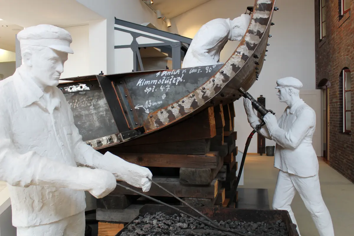 Weiße Figuren stellen historische Werftarbeiter bei der Schiffskonstruktion im Museum in Bremerhaven dar.