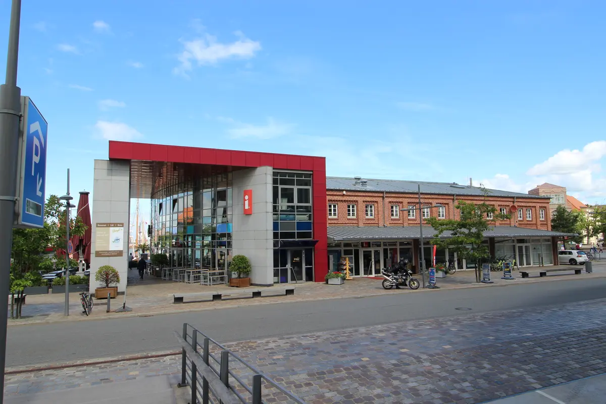 Außenansicht des modernen Gebäudes der Tourist-Information mit rotem Dachakzent und Klinkerbau in Bremerhaven.