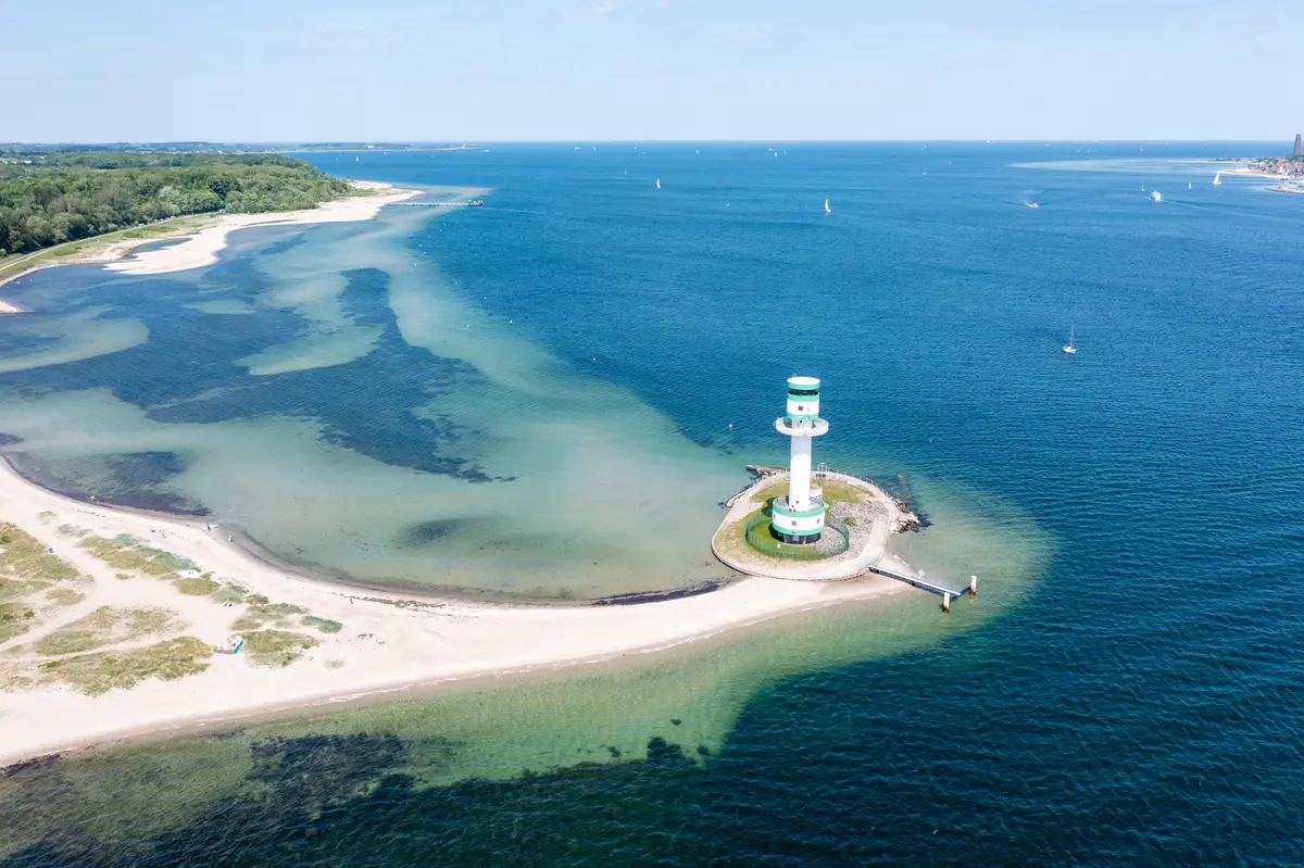 Luftaufnahme des grün-weiß gestreiften Leuchtturms Friedrichsort am Sandstrand der Kieler Förde in Kiel.