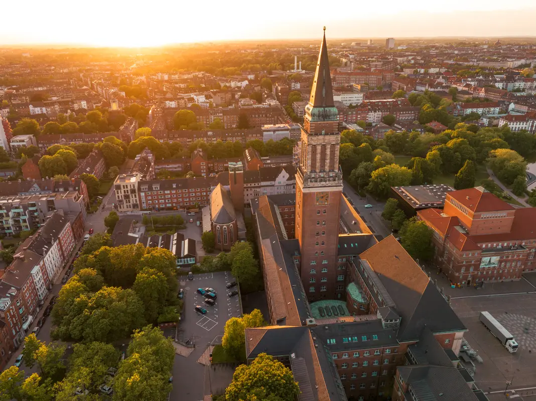 Luftbild des imposanten Rathausturms in Kiel im goldenen Sonnenuntergangslicht mit Blick über die Stadt.