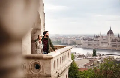 Ein Paar auf der Fischerbastei in Budapest blickt über die Donau auf das Ungarische Parlament und die Stadt.