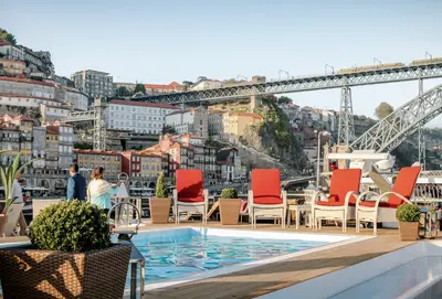 Blick auf das Sonnendeck der A-ROSA ALVA mit Pool, Liegestühlen und der Skyline von Porto mit Brücke im Hintergrund.