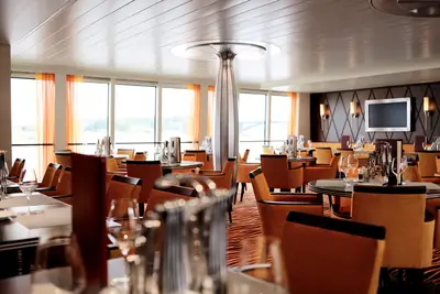 Ein stilvoll eingerichteter Restaurantbereich an Bord der A-ROSA Aqua mit zahlreichen eingedeckten Tischen und großen Fenstern mit Flussblick.