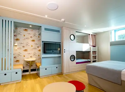 Helle Familienkabine auf einem Flusskreuzfahrtschiff mit Doppelbett, Etagenbetten und maritimer Tapete mit Fischen.