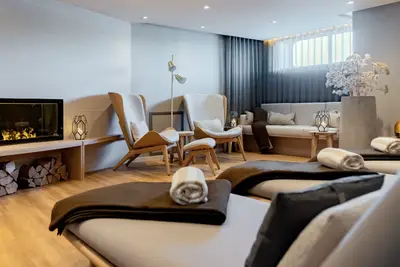 Eleganter Ruheraum im SPA-Bereich mit bequemen Liegen, Sesseln, Kamin und warmem Licht, ideal zur Entspannung.