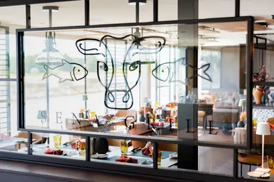 Restaurant SENA GRILL an Bord der A-ROSA SENA mit modern gedeckten Tischen und stilisierten Tierzeichnungen auf der Glasfront, Blick auf den Rhein.