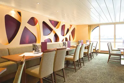 Modernes Restaurant auf der A-ROSA SILVA mit stilvoller Wandgestaltung, Tischen, Stühlen und Flussblick durch große Fenster.