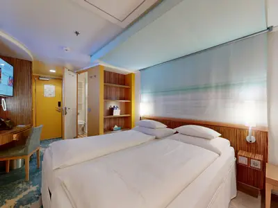 Moderne Innenkabine an Bord der AIDAdiva mit zwei Einzelbetten, einem Schreibtisch und TV. Das Badezimmer ist im Hintergrund zu sehen. Helle und funktionale Einrichtung.