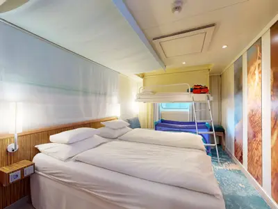 Geräumige Aussenkabine an Bord der AIDAluna mit einem komfortablen Doppelbett, einem Hochbett und einem blauen Babybett. Die Kabine ist hell eingerichtet, mit Holzelementen und modernen Wandbildern.