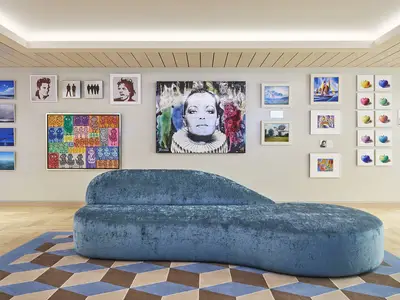 Die moderne Kunstgalerie an Bord der AIDAnova. Zahlreiche gerahmte Kunstwerke an den Wänden, dazu eine blaue Samtliege auf einem Teppich.
