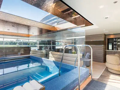 Moderner Indoor-Pool auf der Amadeus Amara. Grosse Fenster mit Flussblick. Angrenzende Lounge mit Sitzgelegenheiten und Getränkestation. Edle Decke mit Glasdachfenster.