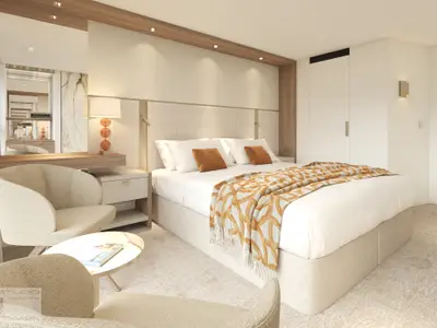 Helles, modernes Schlafzimmer in einer Schiffssuite auf der Amadeus Aurea mit Doppelbett, weisser Bettwäsche, orangefarbenem Überwurf. Dazu Nachttische, Schminktisch mit Spiegel und ein Sessel.