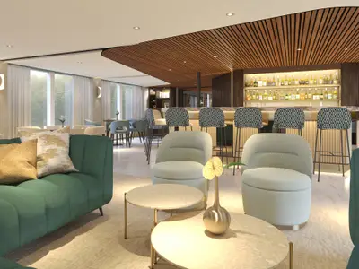 Moderner Bar- und Loungebereich an Bord der AMADEUS Mira. Grüne Sofas, helle Sessel und Couchtische im Vordergrund. Eine lange Bar mit Barhockern und beleuchteten Flaschen im Hintergrund. 