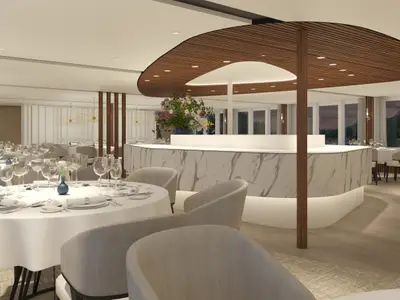 Ein elegantes, modernes Restaurant auf der AMADEUS Nova mit zahlreichen weiss gedeckten Tischen, bereit für Gäste. Im Hintergrund befindet sich eine stilvolle Marmorbar.