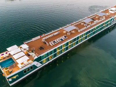 Luftaufnahme der AMADEUS Provence auf ruhigem Wasser. Das Sonnendeck zeigt Pool, Sonnenschirme, Liegen, Tische und Fahrräder.