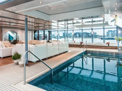 Eleganter Indoor-Pool auf der AMADEUS Queen mit angrenzendem Loungebereich und Panoramablick auf die Stadt.