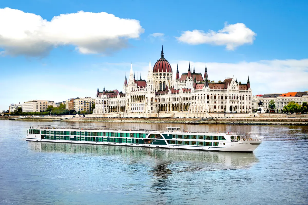 Flusskreuzfahrtschiff Amadeus Star auf der Donau vor dem ungarischen Parlament in Budapest.