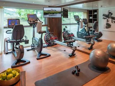 Modernes Fitnessstudio auf der AMADEUS Star mit Blick auf den Fluss und Life Fitness Geräten.