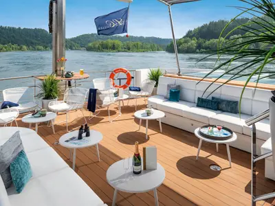 Sonnendeck auf der AMADEUS Star mit eleganten Sitzgelegenheiten, Whirlpool und Flussblick bei Tag.