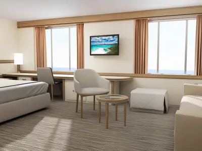 Geräumige, moderne Suite auf der Carnival Adventure. Links ein Doppelbett, mittig ein Schreibtisch mit zwei Stühlen, rechts ein Sofa und ein Fenster mit Meerblick.