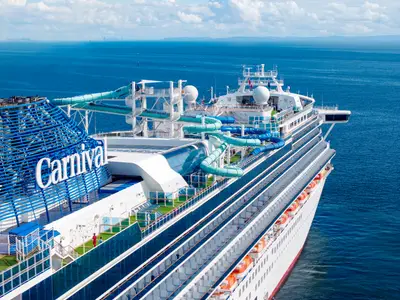 Blick von oben auf das Heck der Carnival Adventure. Auffällig sind die blauen und türkisen Wasserrutschen auf den oberen Decks. Sie befindet sich auf dem offenen Meer.
