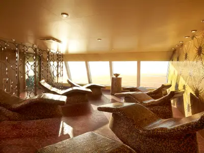 Luxuriöser Spa-Ruheraum auf der Carnival Breeze mit vielen Mosaik-Liegen. Große Fenster bieten Meerblick. Dekorative Mosaikwand und metallene Trennwände.