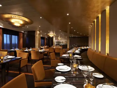 Luxuriöses Spezialitätenrestaurant auf der Carnival Breeze. Elegante Tische, senfgelbe Samtstühle. Goldene Decken und Säulen schaffen eine exklusive Abendstimmung.