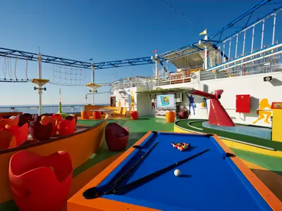 Ein weitläufiges Sportdeck auf der Carnival Breeze mit einem Hochseilgarten, einer Minigolfanlage und einem Billardtisch. Bunte Möbel und Installationen unter strahlend blauem Himmel über dem Meer.