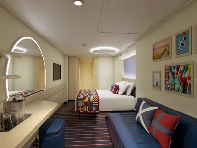 Geräumige, moderne Kabine der Carnival Celebration mit Doppelbett, blauer Sitzbank, maritimem Teppich und gerahmten Wandbildern.