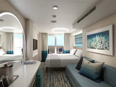 Eine helle, moderne Balkonkabine auf der Carnival Celebration mit Doppelbett, Sofa, Schreibtisch und einem Balkon, der einen weiten Blick auf das offene Meer bietet. Die Einrichtung ist in warmen Erdtönen gehalten, akzentuiert durch frische Blau- und Türkistöne in Kissen und Vorhängen.