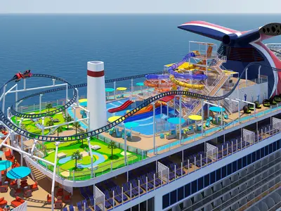 Vogelperspektive auf das bunte Oberdeck der Carnival Celebration bei Tageslicht. Eine Achterbahn, Wasserrutschen und ein Minigolfplatz sind sichtbar, umgeben von Liegestühlen und Pools mit blauem Meer im Hintergrund.