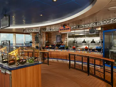Innenansicht des Blue Iguana Cantina Buffets auf der Carnival Celebration. Eine Salsa Bar und Tacos werden mit Blick auf das offene Meer angeboten.