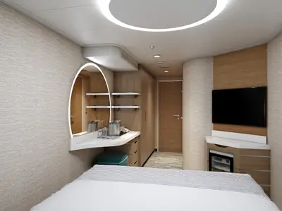 Blick in eine moderne Innenkabine auf der Carnival Celebration mit weißem Bett, ovalem Spiegel mit Beleuchtung, Holzelementen, TV und Minibar.