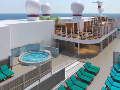 Hochwinkelaufnahme eines sonnigen Sonnendecks der Carnival Celebration mit einem blauen Whirlpool, umgeben von Liegestühlen und einem erhöhten Lounge-Deck mit Cabanas. Das Meer ist im Hintergrund sichtbar.