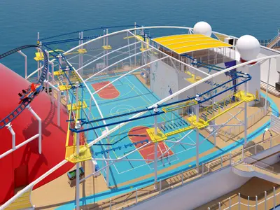 Vogelperspektive auf das Sportdeck der modernen Carnival Celebration mit blauem Basketballplatz, gelbem Hochseilgarten und roter Achterbahn auf dem Meer.