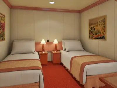 Blick in eine helle Doppelkabine der Carnival Conquest mit zwei getrennten Betten, Nachttischen, Lampen und Wandbildern.