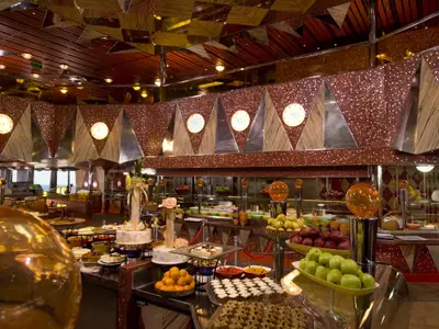 Üppiges Buffet auf der Carnival Dream mit verschiedenen Dessert- und Obststationen. Elegante Dekoration mit runden Leuchten und gemusterten Wänden.