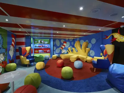 Farbenfroher Kinderbereich im Dr. Seuss-Stil an Bord. Bunte Wände, Möbel und eine gelbe Sofa-Skulptur zum Spielen und Entspannen.