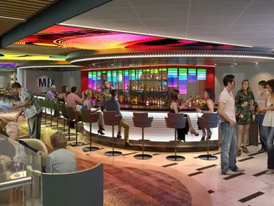 Innenansicht einer lebhaften Bar-Lounge auf der Carnival Festivale. Die Szene zeigt Gäste an einer runden Bar mit bunten Lichtelementen und einer hinterleuchteten Getränkeauslage. Weitere Sitzbereiche sind im Hintergrund zu sehen.