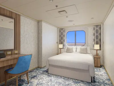 Eine elegant eingerichtete Außenkabine auf der Carnival Firenze mit Doppelbett, blauem Teppich, Holzmöbeln, Schreibtisch und einem runden Fenster mit Blick auf das Meer.
