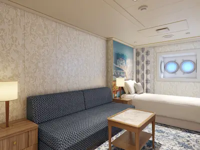 Eine moderne Innenkabine der Carnival Firenze. Rechts ein weißes Einzelbett, links ein gemustertes blaues Sofa. An der Wand eine beleuchtete Porthole-Nische. Die Wände sind mit einem hellen Barockmuster tapeziert.