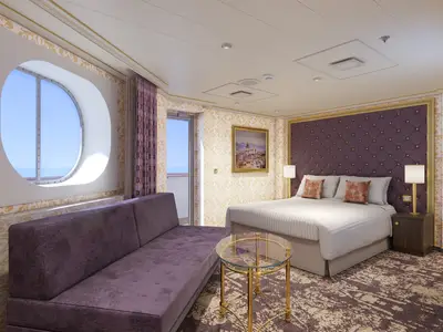 Eine luxuriös eingerichtete Suite auf der Carnival Firenze. Im Vordergrund ein lila Sofa und ein runder Glastisch. Rechts ein großes Bett mit Samtkopfteil. Links ein großes, ovales Fenster und eine Balkontür bieten Meerblick.