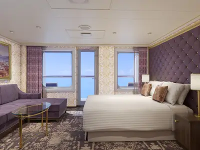 Geräumige und luxuriöse Suite der Carnival Firenze mit großen Fenstern zum Meer, einem Doppelbett mit lila Kopfteil und einer lila Chaiselongue. Die Wände sind mit goldener Damasttapete verziert.