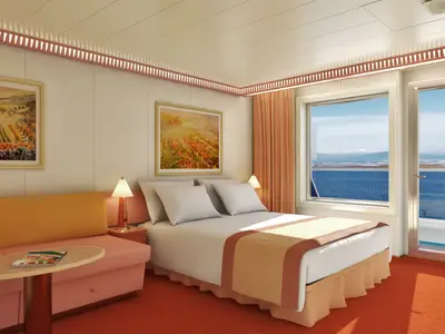 Eine helle, gemütliche Balkonkabine auf der Carnival Freedom mit Doppelbett, Sofa, Beistelltisch und Meerblick durch Balkontür.