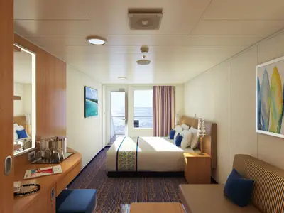 Eine helle Balkonkabine der Carnival Horizon mit einem Doppelbett, Sofa, Schreibtisch und Blick auf das blaue Meer. Seitlich ist eine Bar mit Gläsern sichtbar.