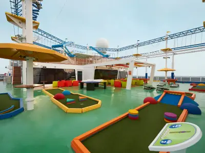 Bunter Minigolfplatz auf dem Oberdeck der Carnival Horizon. Im Hintergrund sind ein Hochseilgarten und eine Lounge-Area unter klarem Himmel zu sehen.