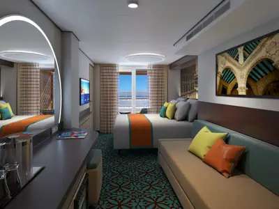 Geräumige, moderne Balkonkabine auf der Carnival Jubilee. Großes Bett, Sofa, Schreibtisch und Balkon mit Meerblick.